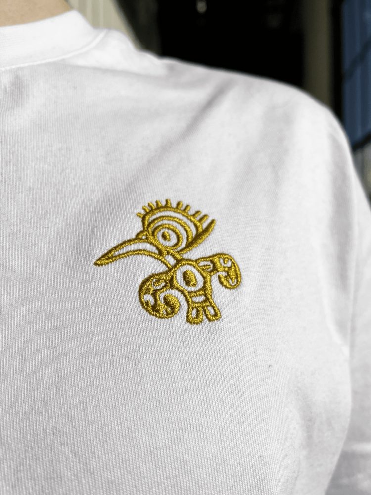 Weißes T-Shirt mit goldenem Mio Mio Tukan eingestickt auf der linken Brust